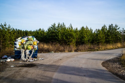 Worker preparing equipment for a garden clearance job with safety signage visible